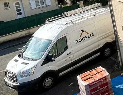 Camionnette de couvreur Rooflia stationnée devant un chantier de toiture à Massy